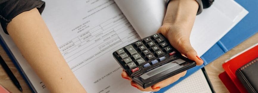 person holding black calculator while using laptop